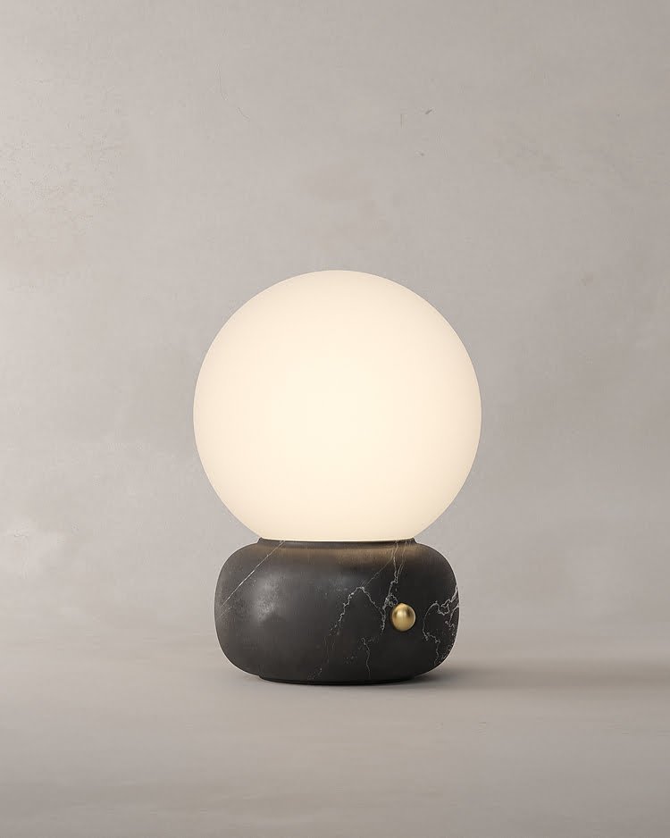 Lámpara de mesa NAGA hecha de mármol negro y latón con difusor esférico de vidrio opalino diseñada por Bandido Studio.